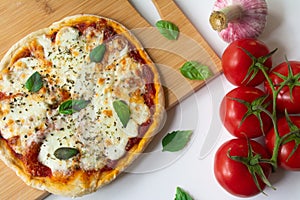 Homemade Italian pizza Napoletana with fresh tomato and garlic sauce, mozzarella cheese and basil leaves