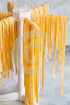 Homemade Italian tagliatelle hanging on a pasta drying rack. Fresh noodle drying on drying rack.  Self-made Spaghetti Drying on a