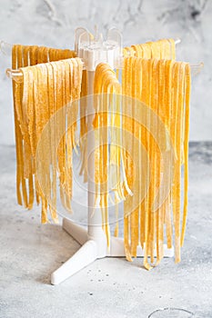 Homemade Italian tagliatelle hanging on a pasta drying rack. Fresh noodle drying on drying rack.  Self-made Spaghetti Drying on a