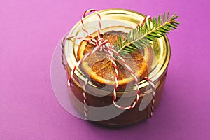 Homemade jam in a decorated jar with orange slice and fir tree twig. Winter gift