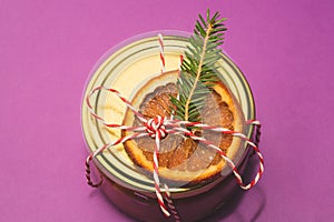 Homemade jam in a decorated jar with orange slice and fir tree twig. Winter gift