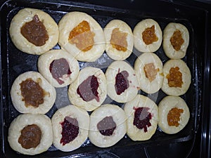 Homemade jam filled raw Kolachi pastry proofing on a baking pan photo