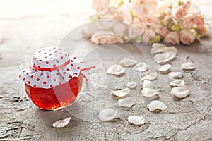 Homemade jam of rose petals on table with bouquet of roses