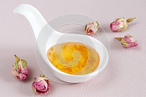 Homemade jam of rose petals in white ceramic bowl on pink background. Traditional Turkish dessert. Selective focus