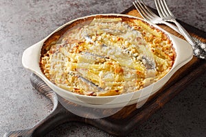 Homemade Jansson\'s temptation made from potatoes, onion and sprats closeup on the baking dish. Horizontal