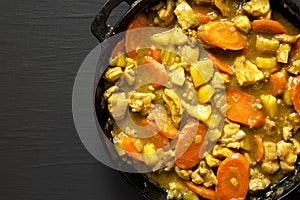 Homemade Japanese Chicken Curry in a cast-iron pan on a black background, top view. Flat lay, overhead, from above. Space for text