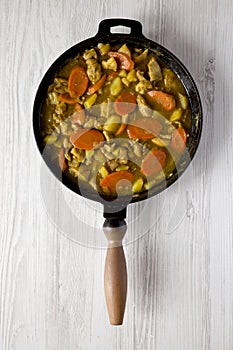 Homemade Japanese Chicken Curry in a cast-iron pan on a white wooden background, top view. Flat lay, overhead, from above