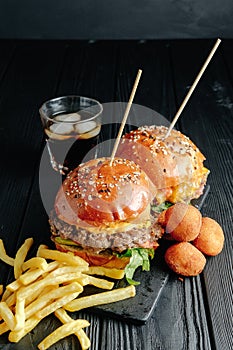 Homemade juicy burgers on wooden board, cheese balls. with French fries and glass of cola