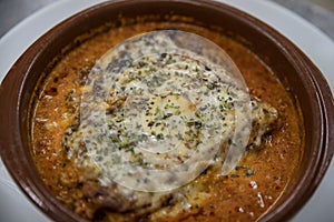 Homemade lasagna baked in a terracotta round pot, individual portion of the traditional Italian dish