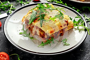 Homemade lasagna with minced beef bolognese and bechamel sauce topped wild arugula, parmesan cheese