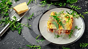 Homemade lasagna with minced beef bolognese and bechamel sauce topped wild arugula, parmesan cheese