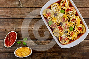 Homemade lasagna rolls in a baking dish on a wooden background. Top view