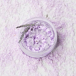 Homemade lavender body scrub in a bowl on lavender bath salt background. Top view, copy space. SPA concept