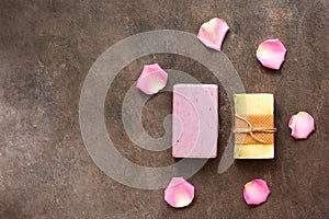 Homemade lavender and herbal soap bars decorated with rose petals. Dark brown grunge background. Top view, flat lay