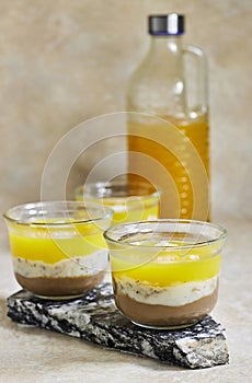 Homemade layered vegan dessert of baked coconut cream and chocolate marble stone board with orange juice bottle