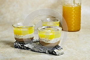 Homemade layered vegan dessert of baked coconut cream and chocolate marble stone board with orange juice bottle