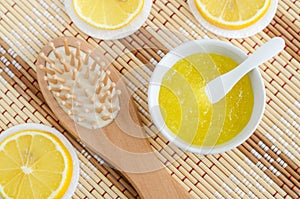 Homemade lemon fruit scrub bath salt, foot soak, facial or hair mask in a small white bowl and wooden hairbrush. Natural beauty