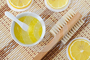 Homemade lemon fruit scrub bath salt, foot soak, facial or hair mask in a small white bowl and wooden hairbrush. Natural beauty