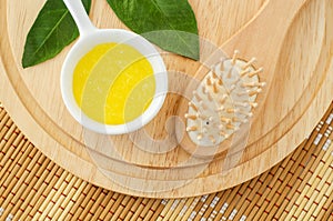 Homemade lemon fruit scrub mask in a small white bowl and wooden hair brush. Natural beauty treatment and spa recipe. Top view