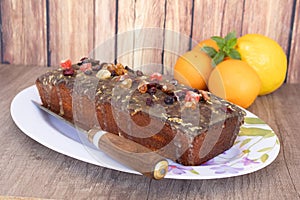 Homemade lemon and orange pudding with fruits on a white platter with vintage-style flower drawings on a wooden table, some citrus