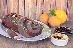 Homemade lemon and orange pudding with fruits on a white platter with vintage-style flower drawings on a wooden table, some citrus