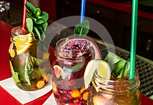 Homemade lemonade ice tea colorful icetea drink with fresh sweet fruits mint leaves in glass on the rocks with straw