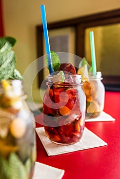 Homemade lemonade ice tea colorful icetea drink with fresh sweet fruits mint leaves in glass on the rocks with straw