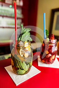 Homemade lemonade ice tea colorful icetea drink with fresh sweet fruits mint leaves in glass on the rocks with straw