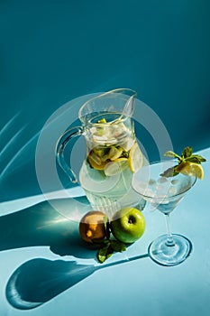 Homemade lemonade with lemon, mint and apple on a blue background