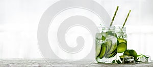 Homemade lime lemonade with cucumber, rosemary and ice, white background. Cold beverage for hot summer day. Copyspace