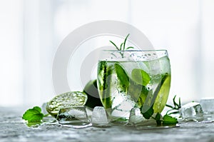 Homemade lime lemonade with cucumber, rosemary and ice, white background. Cold beverage for hot summer day. Copyspace