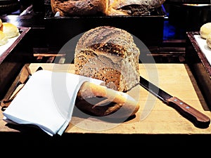 Homemade loaf of whole grain bread and French Baguette with knife on wooden board. Mostly served with butter or jam.