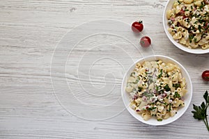 Homemade Macaroni Salad in white bowls on a white wooden background, top view. Flat lay, overhead, from above. Copy space