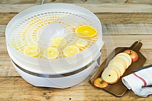 Homemade machine to dehydrate food with orange slices and kitchen table with apple slices