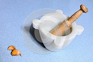 A homemade marble's pestle over a blue silestone desk with garlic