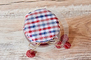 Homemade marmalade. Glass jar with raspberry jam on a wooden background. Preserved berry. Top view