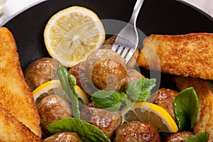Homemade meatballs in frypan with lemon and mint.