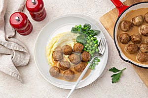 Homemade meatballs with mashed potato, cream sauce and green peas