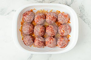 Homemade meatballs with tomato sauce, carrot and spices. Raw ground beef meatballs with rice in a white dish for baking. White