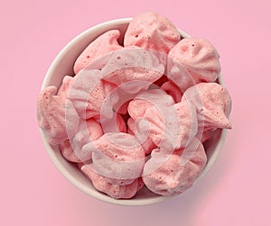 Homemade meringues in white cup on pink.
