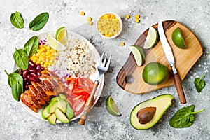 Homemade Mexican chicken burrito bowl with rice, beans, corn, tomato, avocado, spinach. Taco salad lunch bowl.