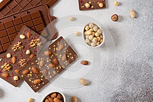 Homemade milk chocolate bars and molds. Chocolate bars, nuts, dried fruits on gray background top view, copy space. Chocolatier,