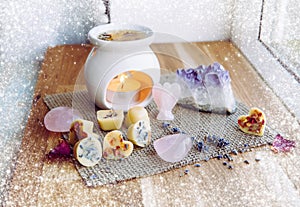 Homemade mini wax melts in aromatherapy lamp diffuser at home interior with rose quartz crystal hearts.