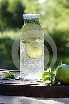 Homemade mojito stands in a transparent bottle in the garden in summer