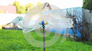 Homemade mole repeller in the garden made from plastic bottles, rotating in the wind. Slow motion, sunset