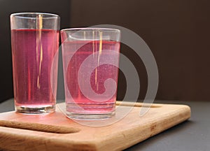 Homemade mors juice compote red pink from alina strawberry blueberries in glasses stand on a board tray on a black background with photo