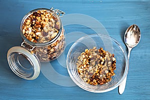 Homemade muesli in a plate on a blue background, healthy breakfast of oatmeal muesli, nuts, seeds and dried fruits