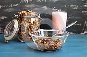 Homemade muesli with yogurt in a plate on a blue background, healthy breakfast of oatmeal muesli, nuts, seeds and dried