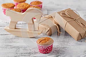 Homemade muffins against giftbox with toy horse