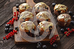 Homemade muffins with red currants and blueberry, covered with white chocolate topping.